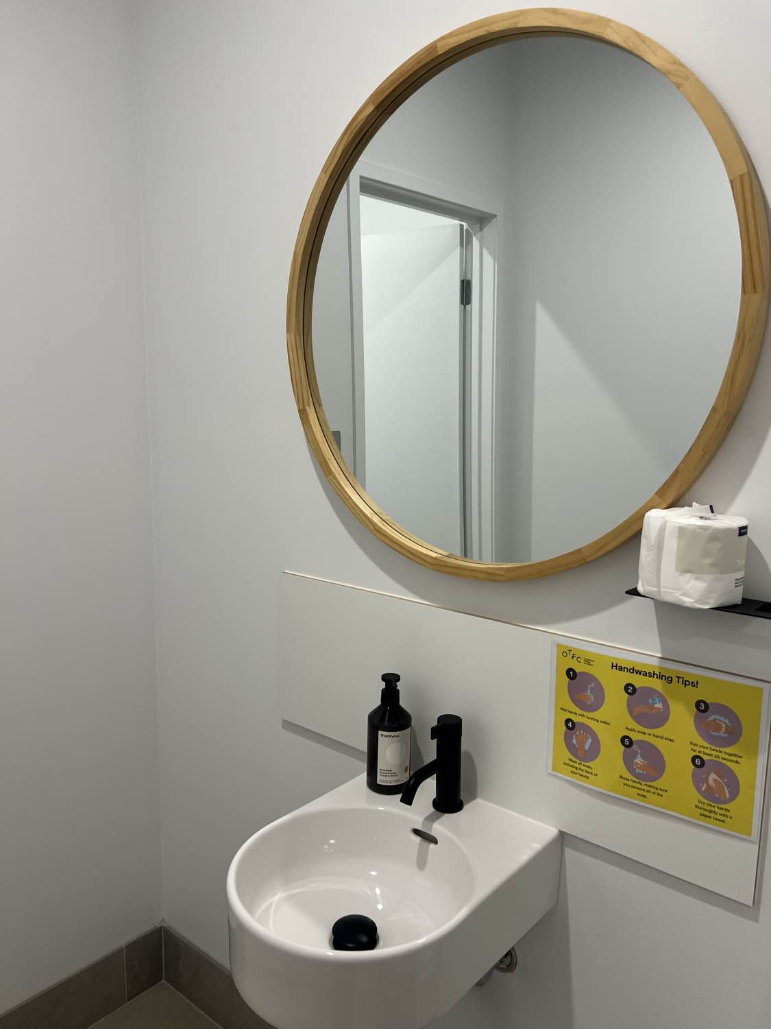 A clinic bathroom cleaned and restocked, handwashing signage in place