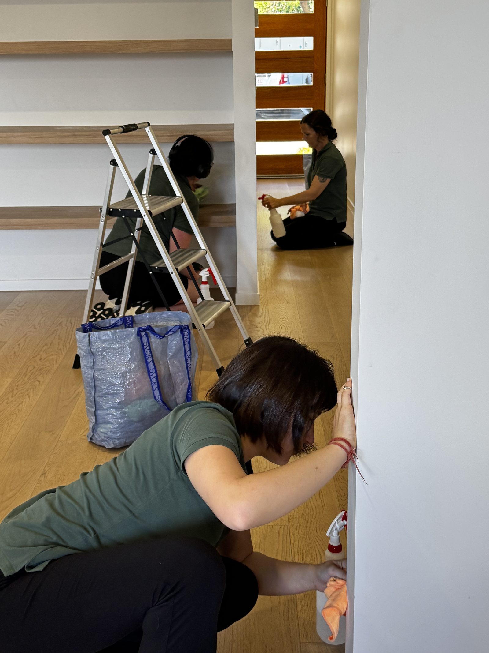 Three Care for a Clean team members detail-cleaning skirting boards and door frames in a home