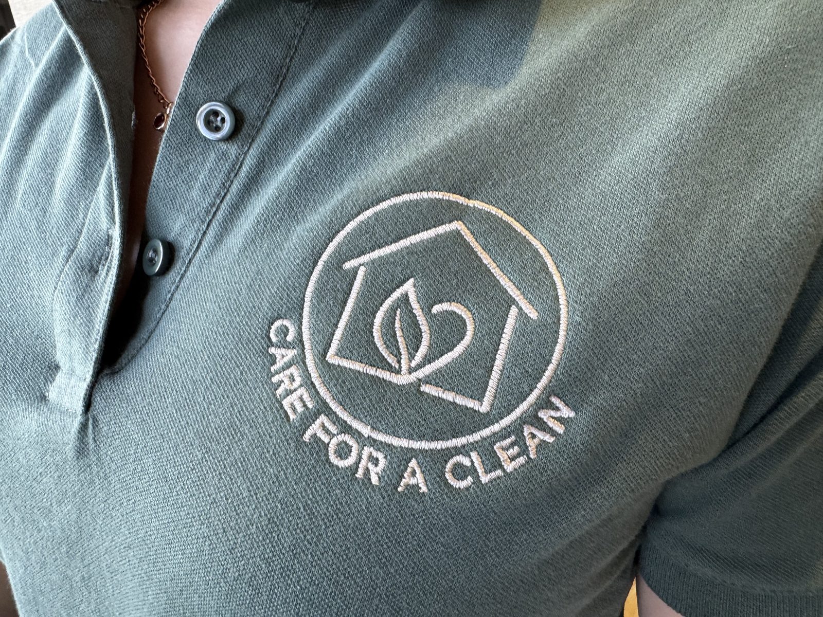 Close-up of the Care for a Clean logo embroidered on a team member's uniform